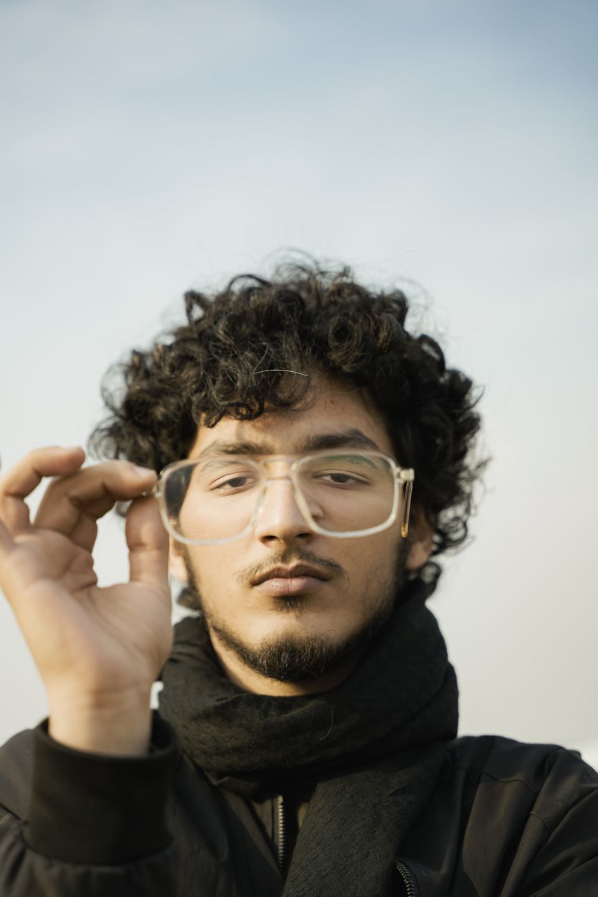 Jeune homme aux boucles frisées et aux lunettes claires, écharpe noire
