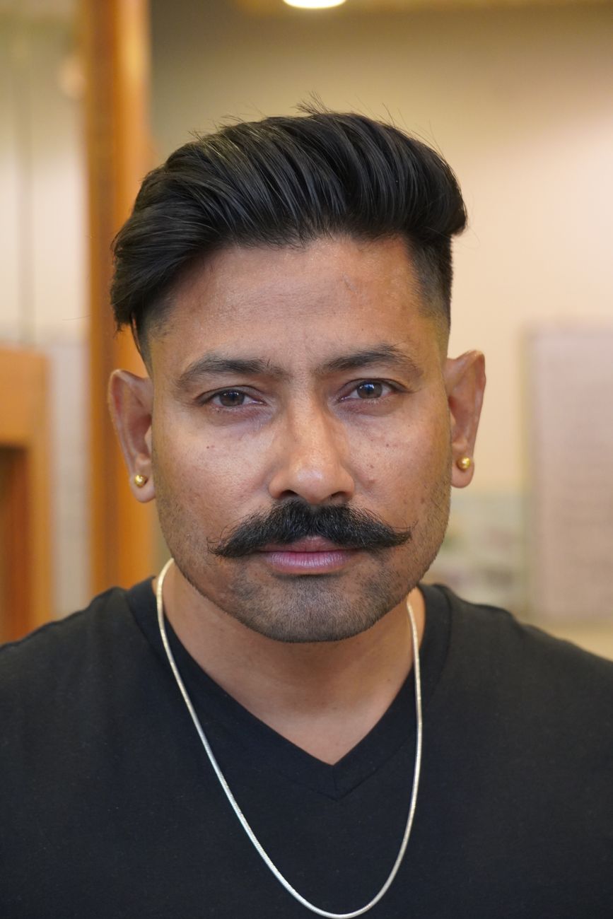 Homme aux cheveux raides coiffés en arrière, côtés dégradés et moustache