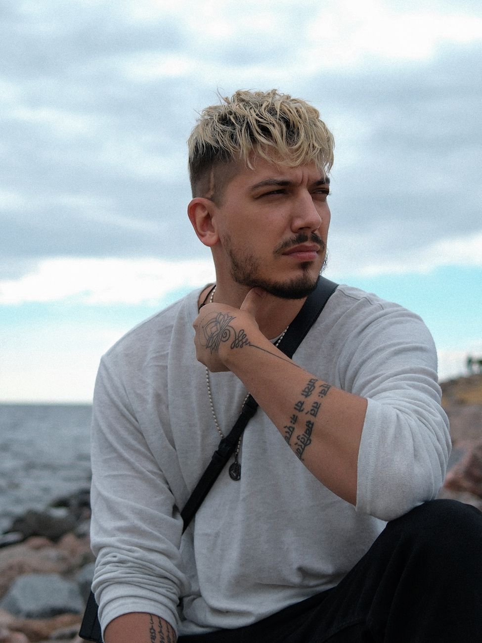 Homme barbu aux cheveux courts éclaircis sur le dessus, au bord de la mer