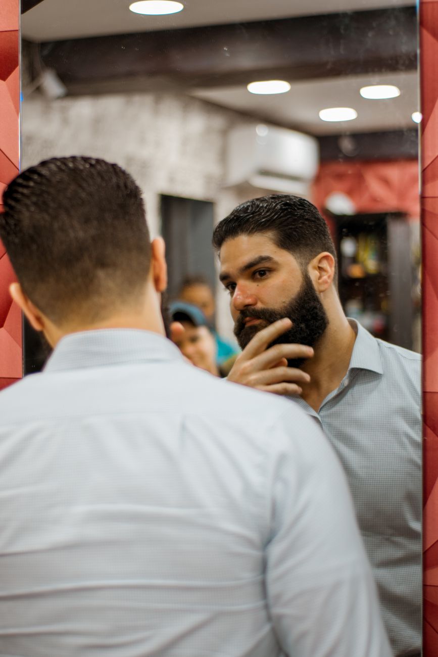 Homme barbu qui se regarde dans le miroir d'un salon