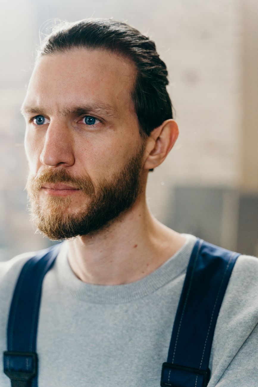 Homme à la barbe moyenne disciplinée, cheveux tirés en arrière, de trois quarts