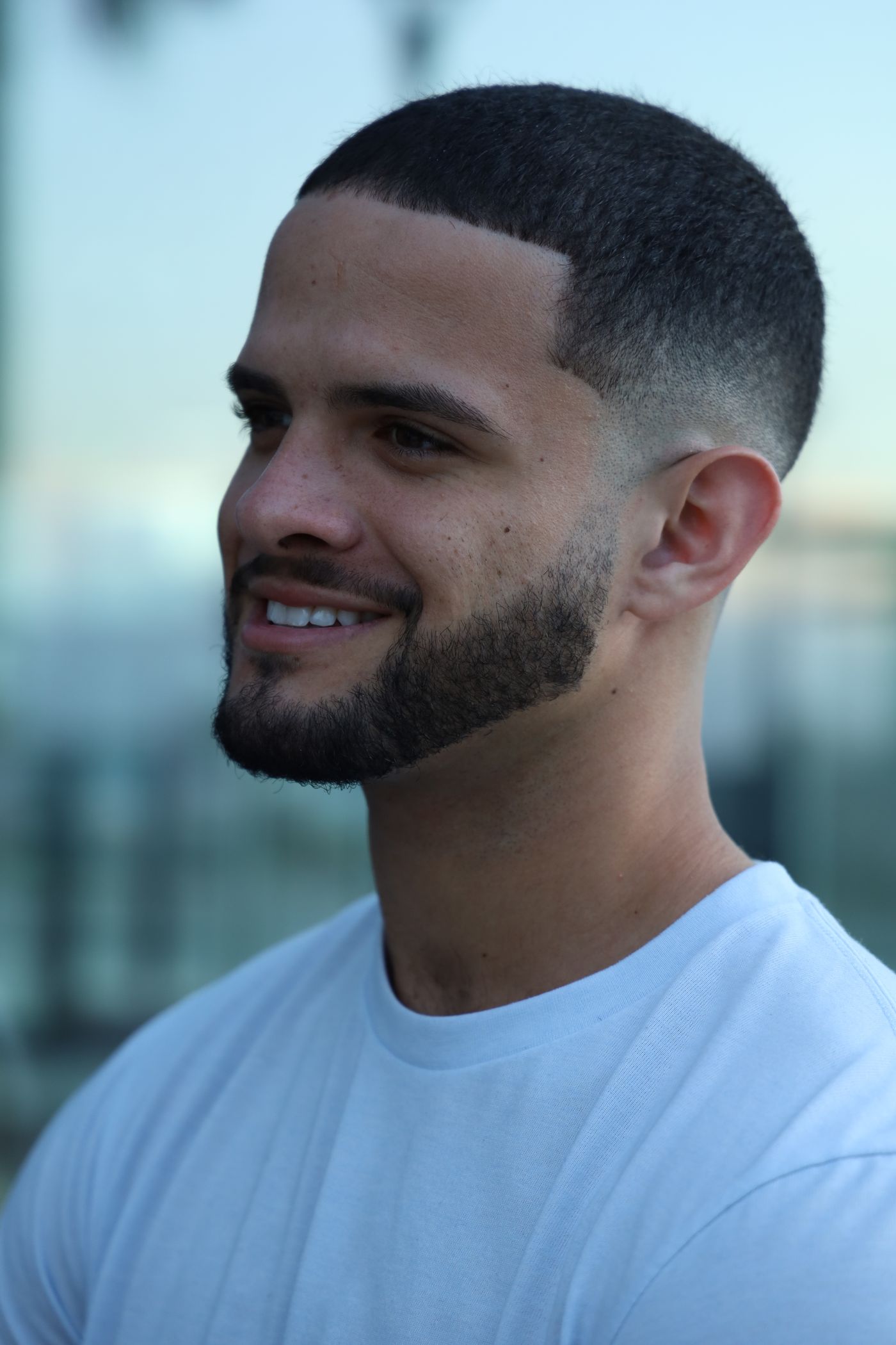 Homme souriant au dessus tondu court, contour net au front et dégradé jusqu'à la peau