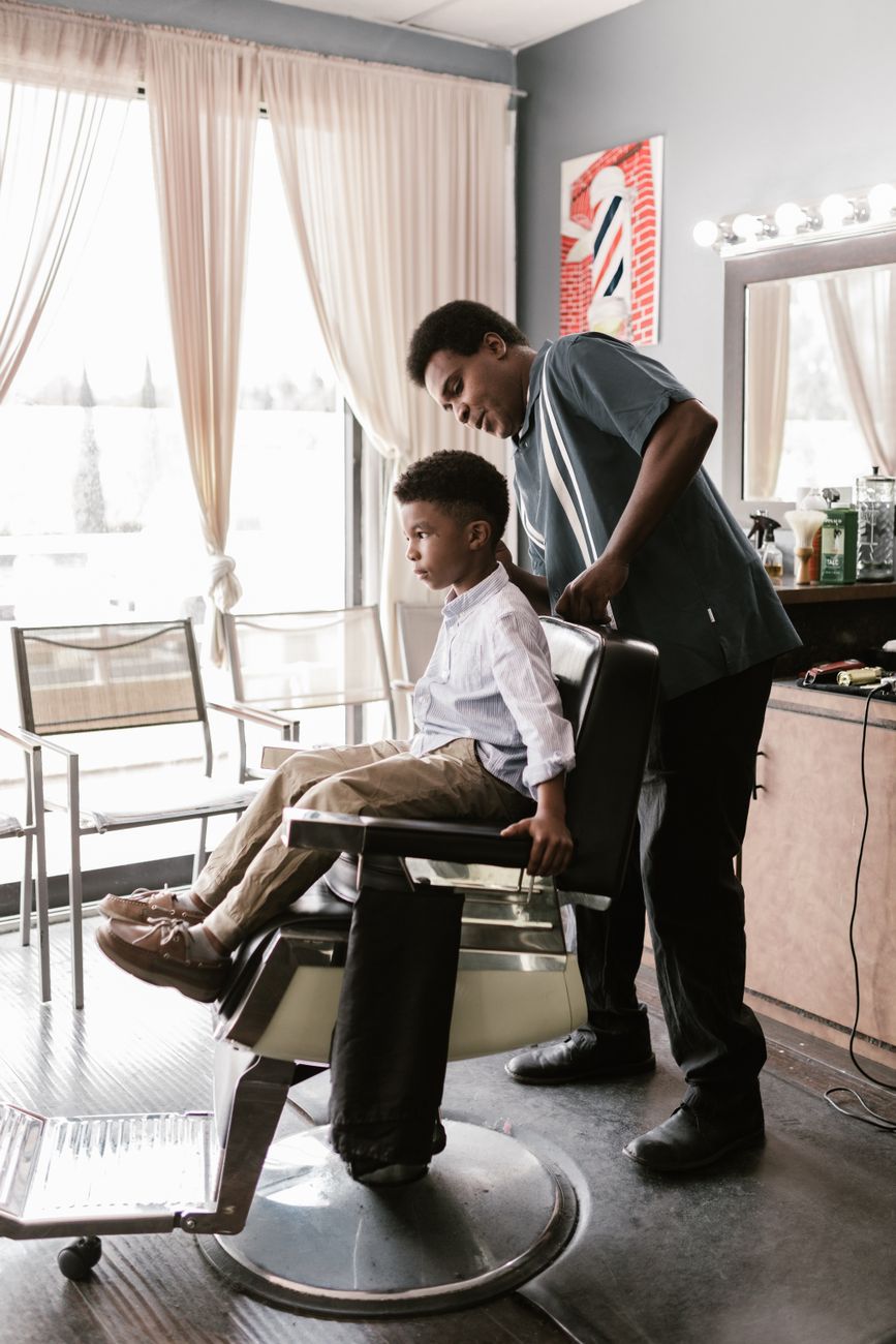 Garçon au fauteuil du barbier, vu de loin dans le salon