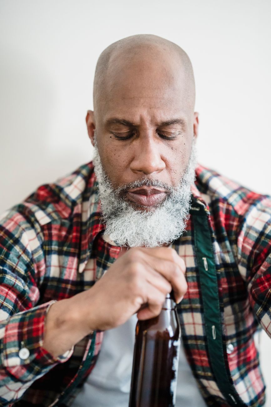Homme barbu aux cheveux blancs, tenant un flacon dans la main