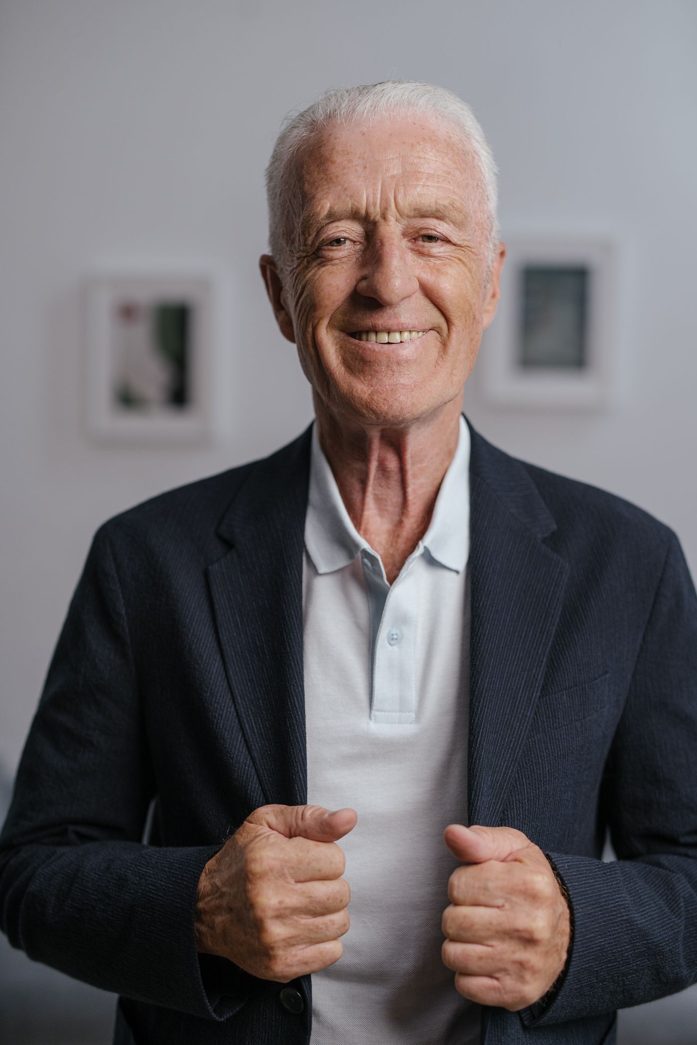 Homme souriant d'environ 70 ans, cheveux blancs courts, veste marine sur polo clair