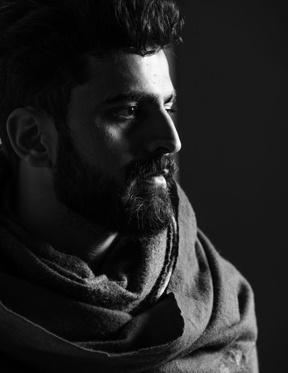 Homme de profil à la barbe fournie qui s'affine vers le menton, en noir et blanc
