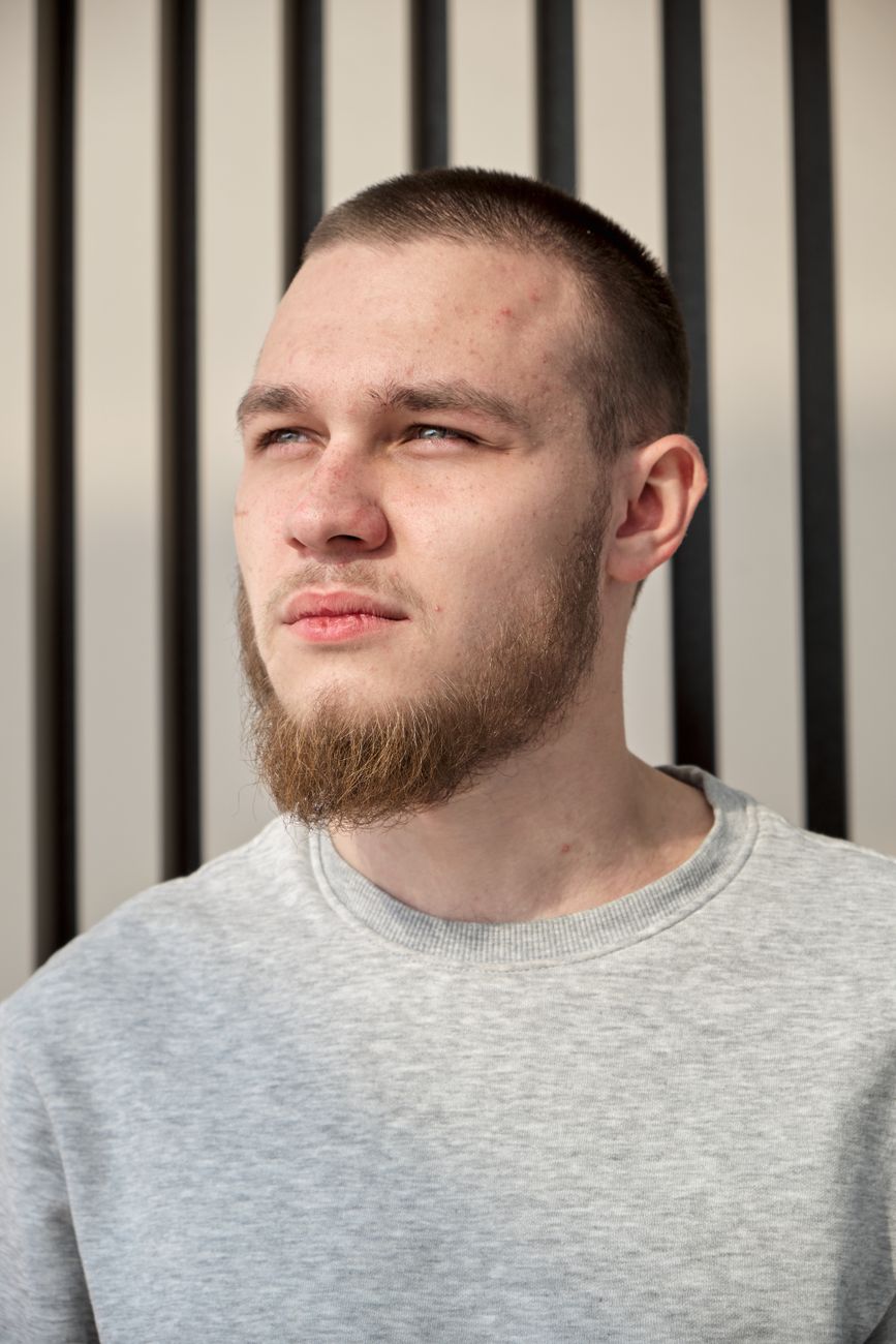 Jeune homme à la barbe peu dense sur les joues, pull gris